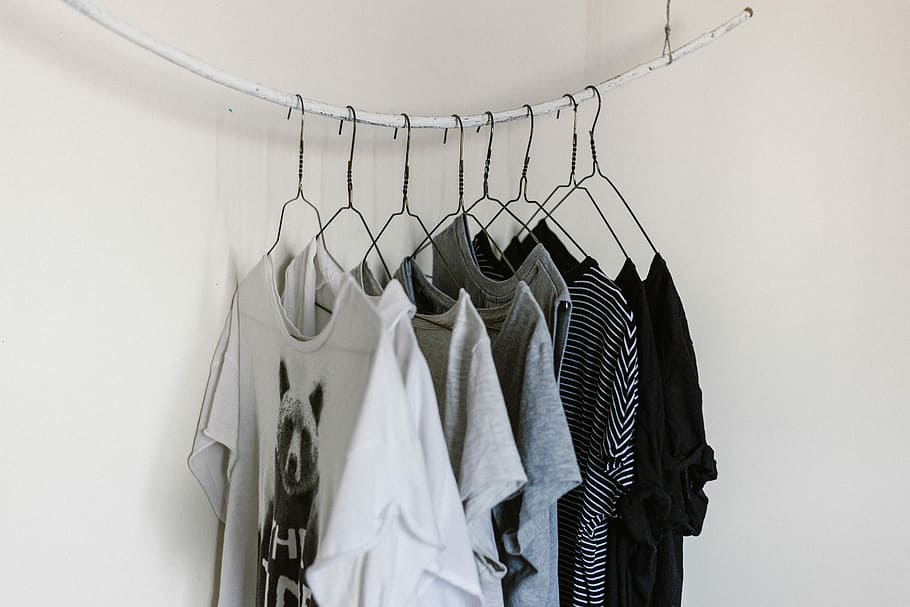 Black and white photo of tee shirts on wire hangers hanging on a line
