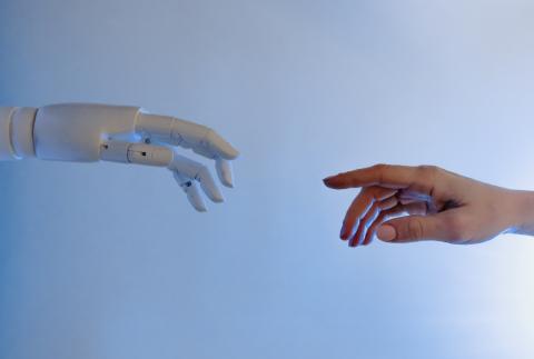 a robot hand and human hand pointing to each other