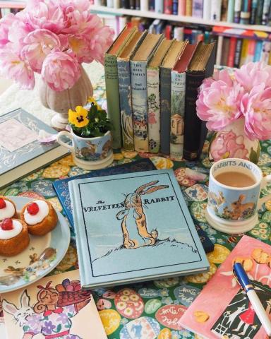 photo of velveteen rabbit with flowers, drink, and sweet treats in the background and a drawing in front of the book