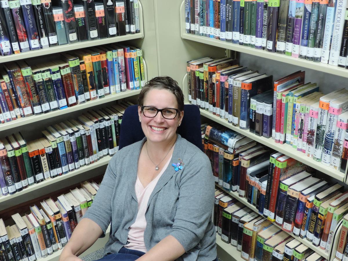 Ms. Deanna sitting in front of book shelves