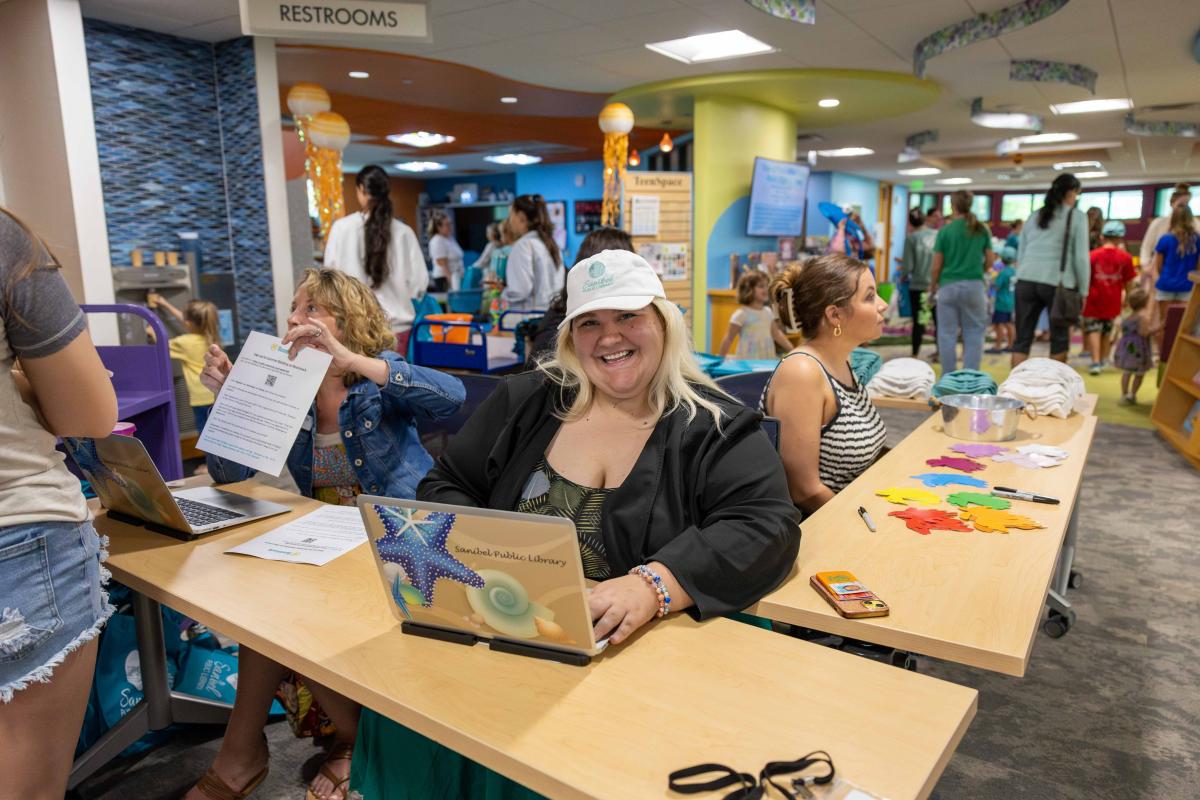 staff at a gathering smiling behind a laptop